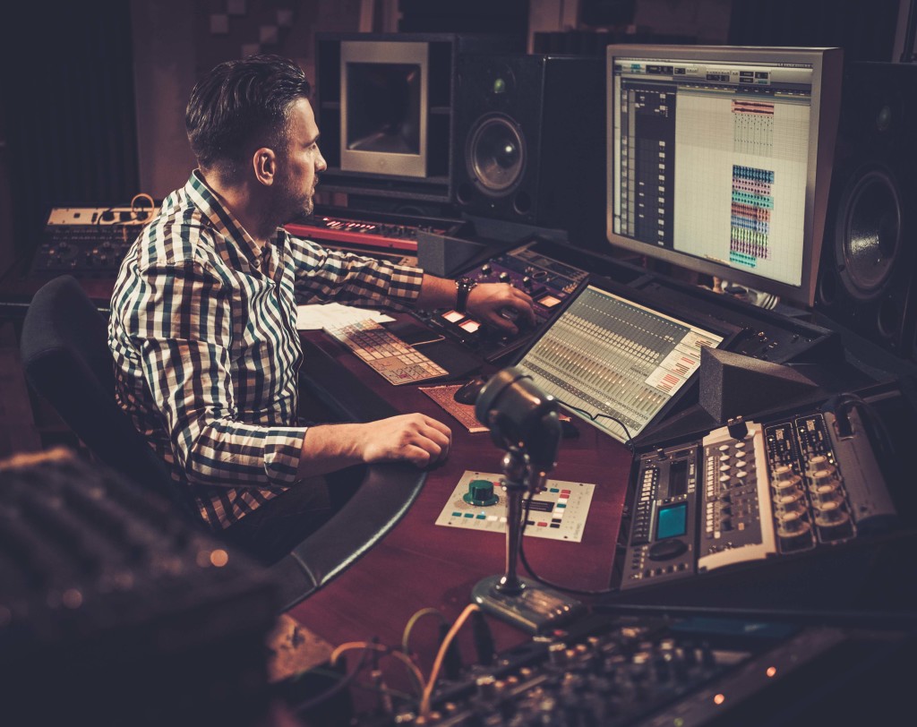 Sound engineer working at mixing panel in the boutique recording studio.; Shutterstock ID 373495885